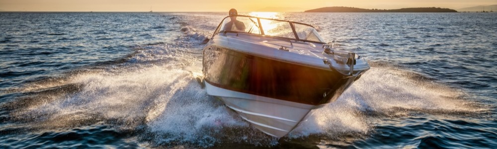 Person boating at sunset on the water with a self-captained boat rental