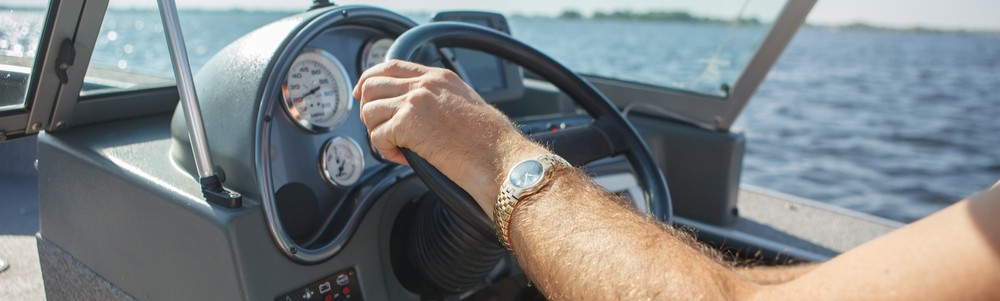 Person with a gold wristwatch driving a Carolina Skiff boat rental